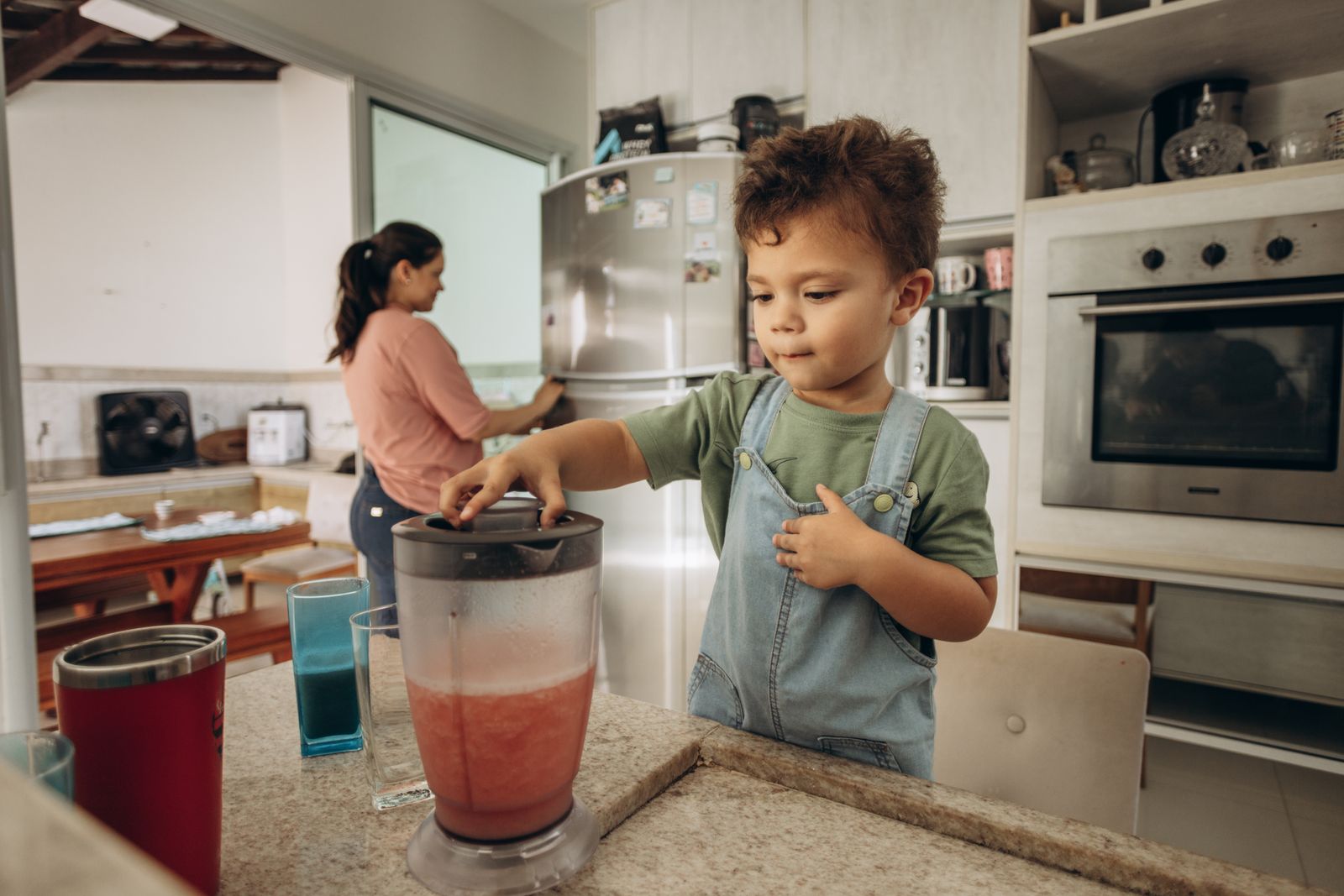 A parent and child using a blender in a home kitchen